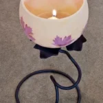 A candle is lit on the floor next to a bowl.