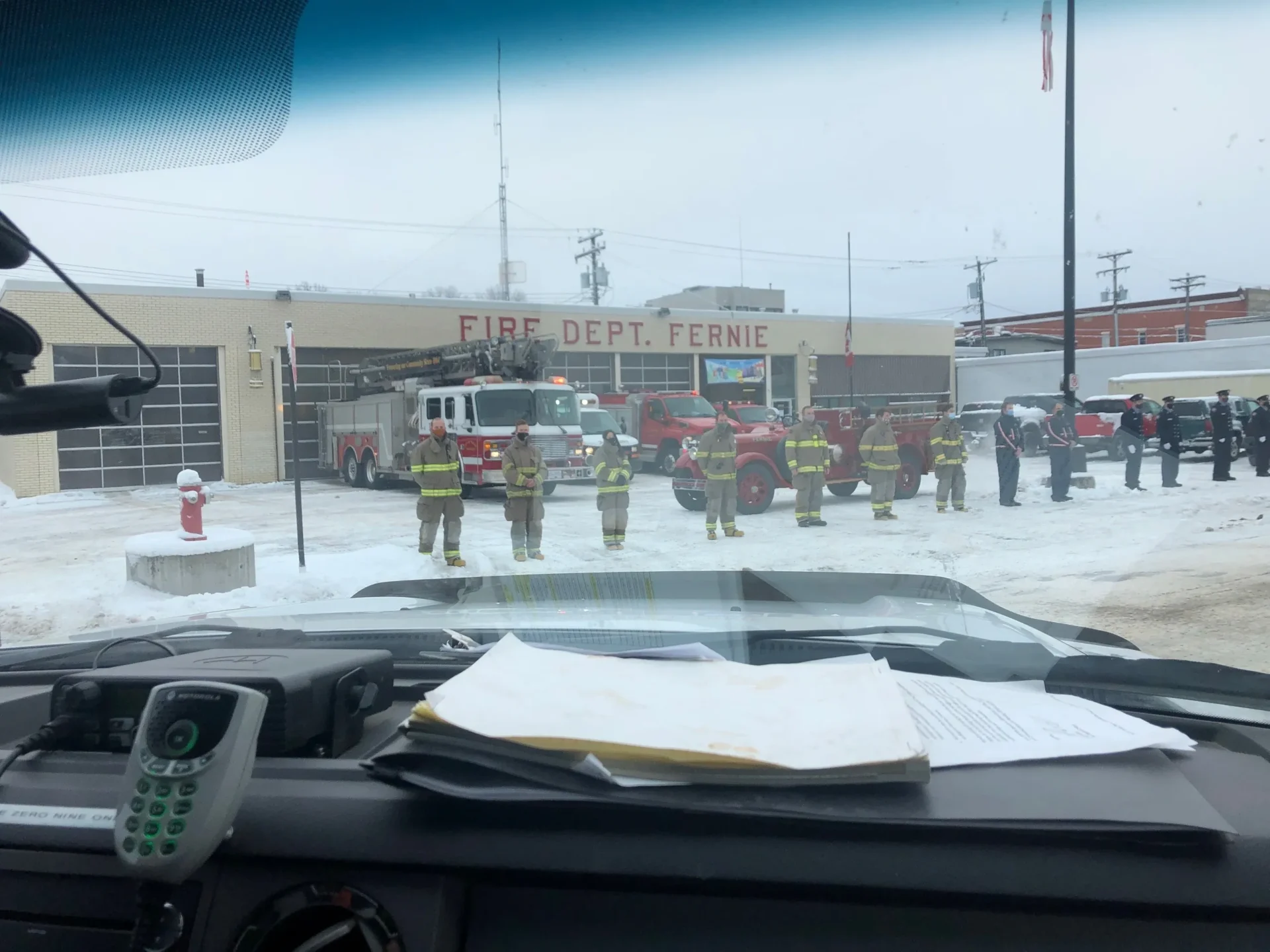 A group of firemen standing in front of a fire station.