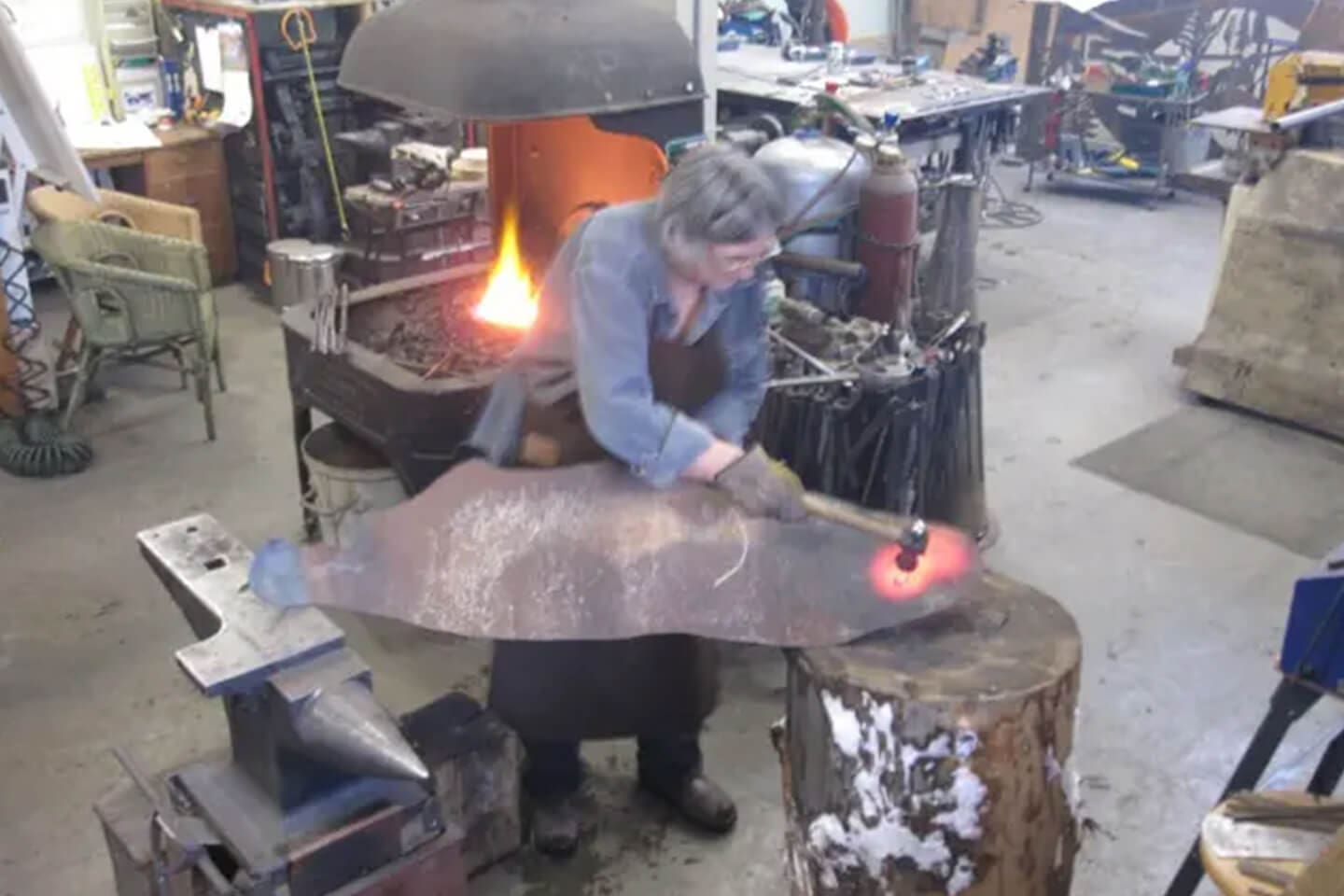 A man is working on an iron object.