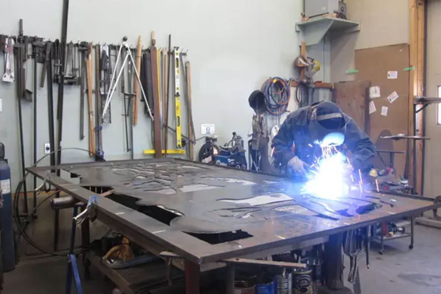 A man welding metal in an industrial setting.