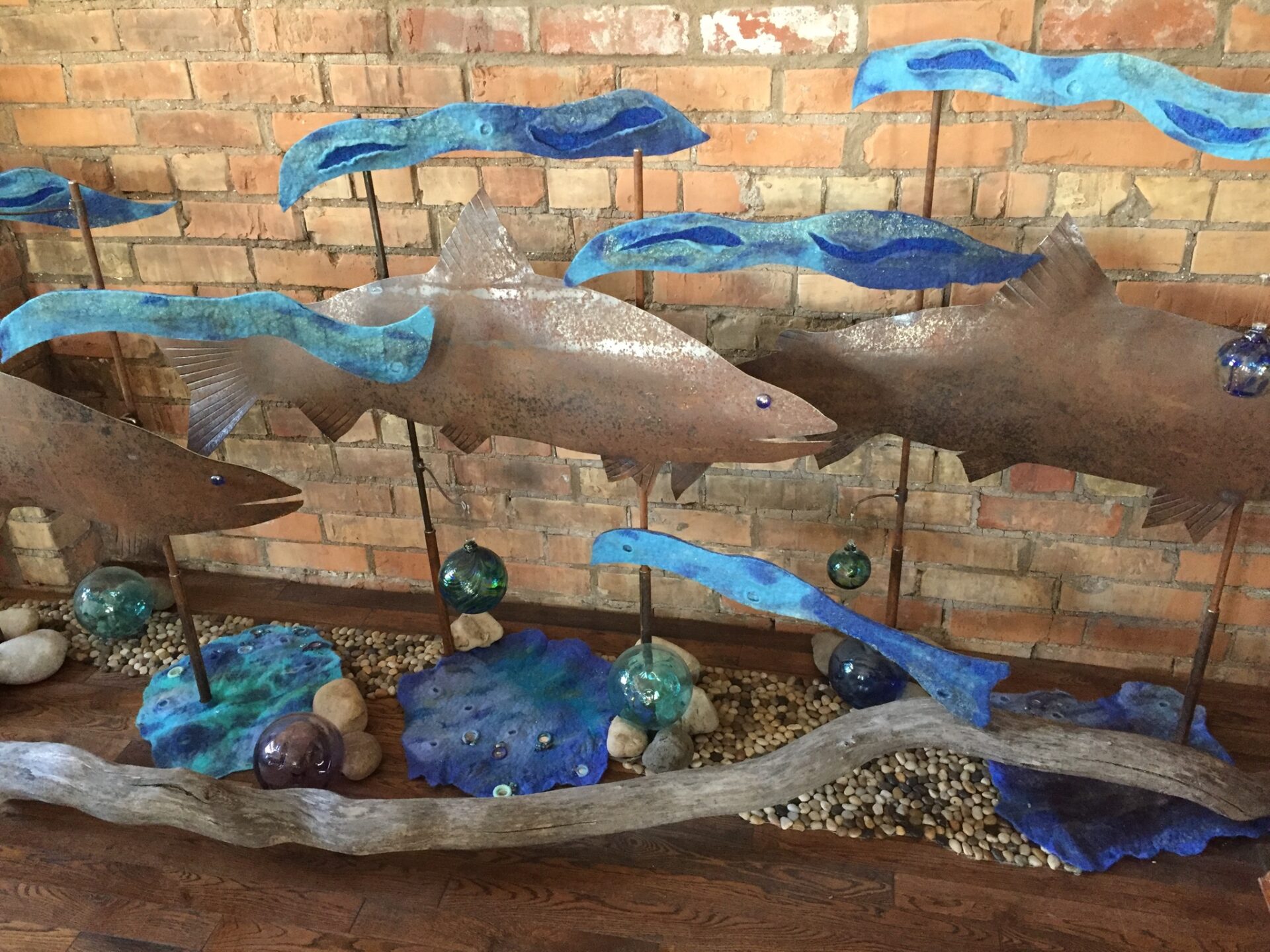 A group of metal dolphins with blue umbrellas.