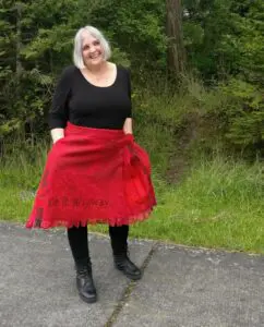 A woman in black shirt and red skirt standing on road.