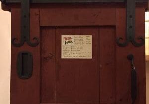 A wooden door with metal handles and a sign.